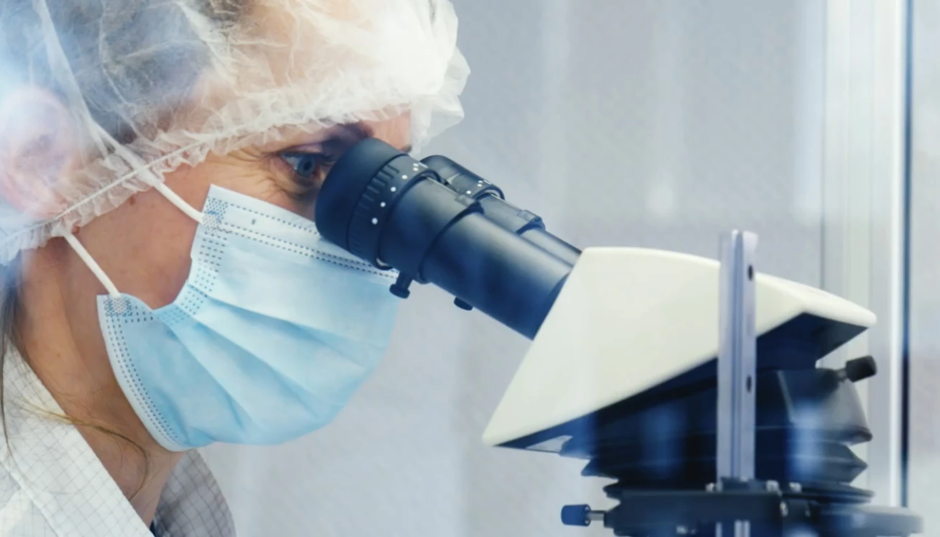 Een wetenschapper kijkt door een microscoop.
